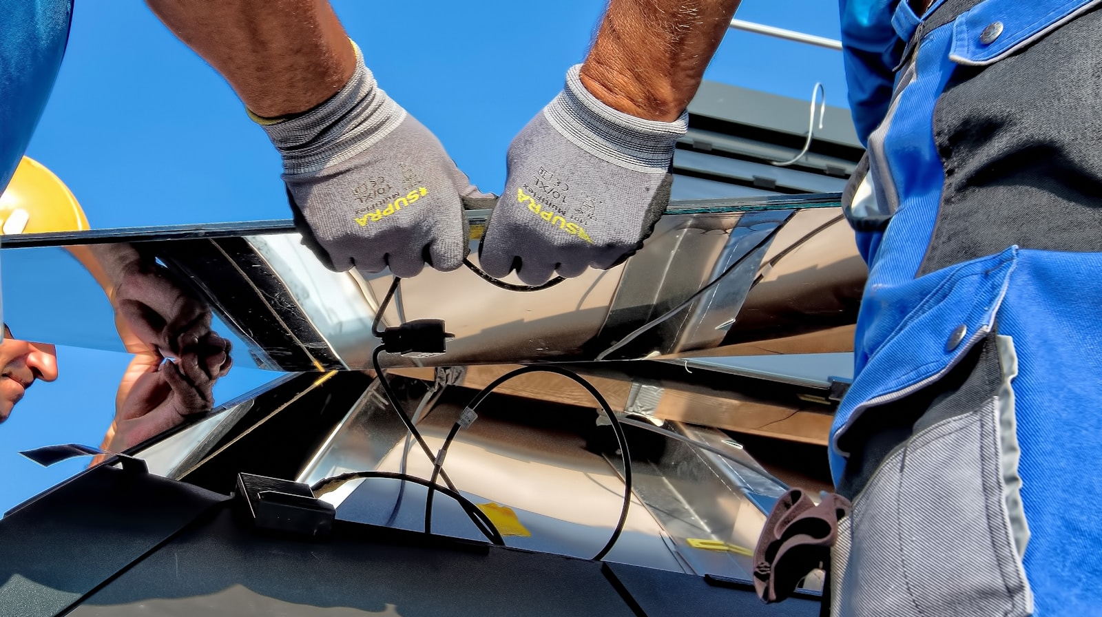 Technicians installing photovoltaic modules on a roof.